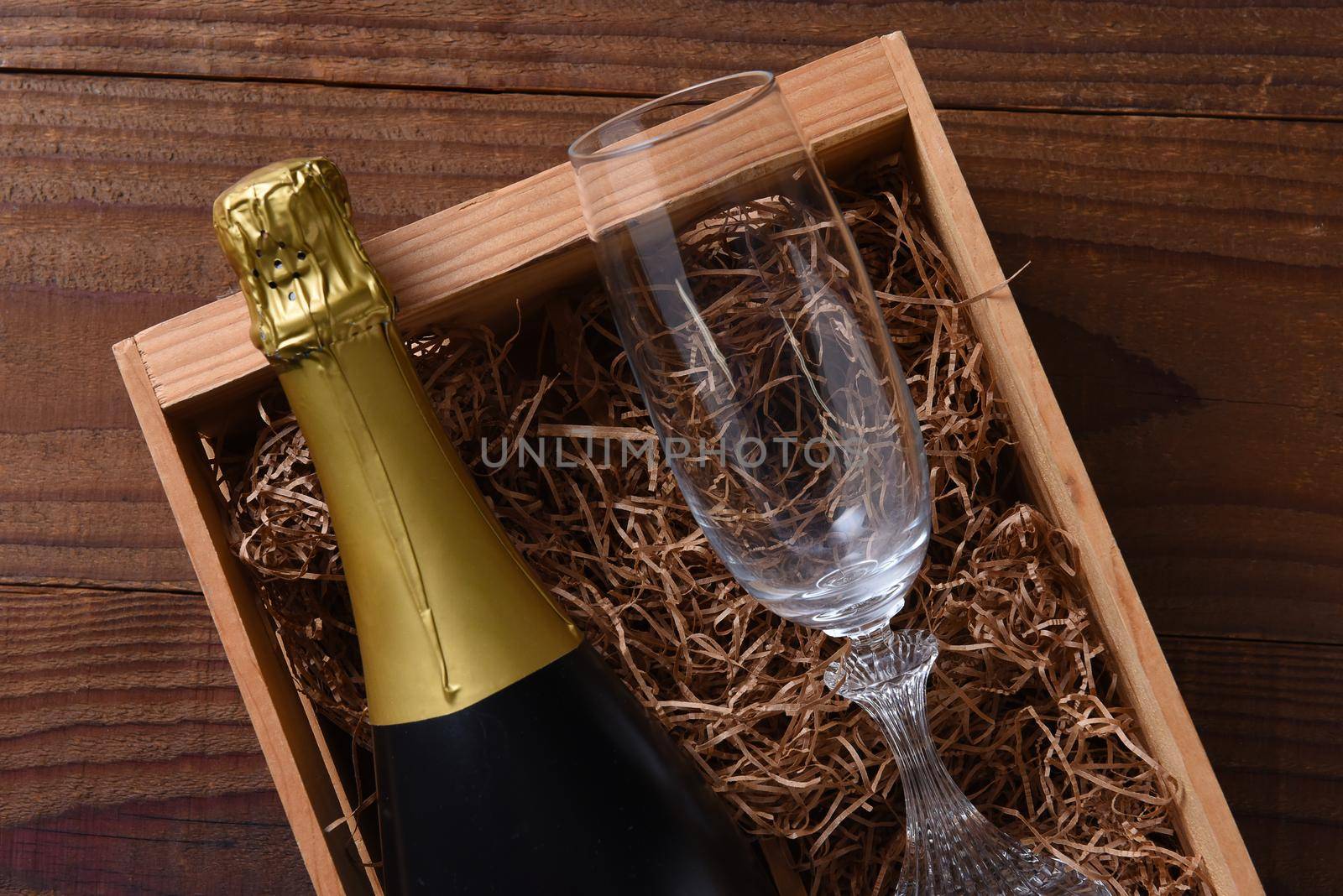 A bottle of Champagne in a wood gift box with a crystal flute. 