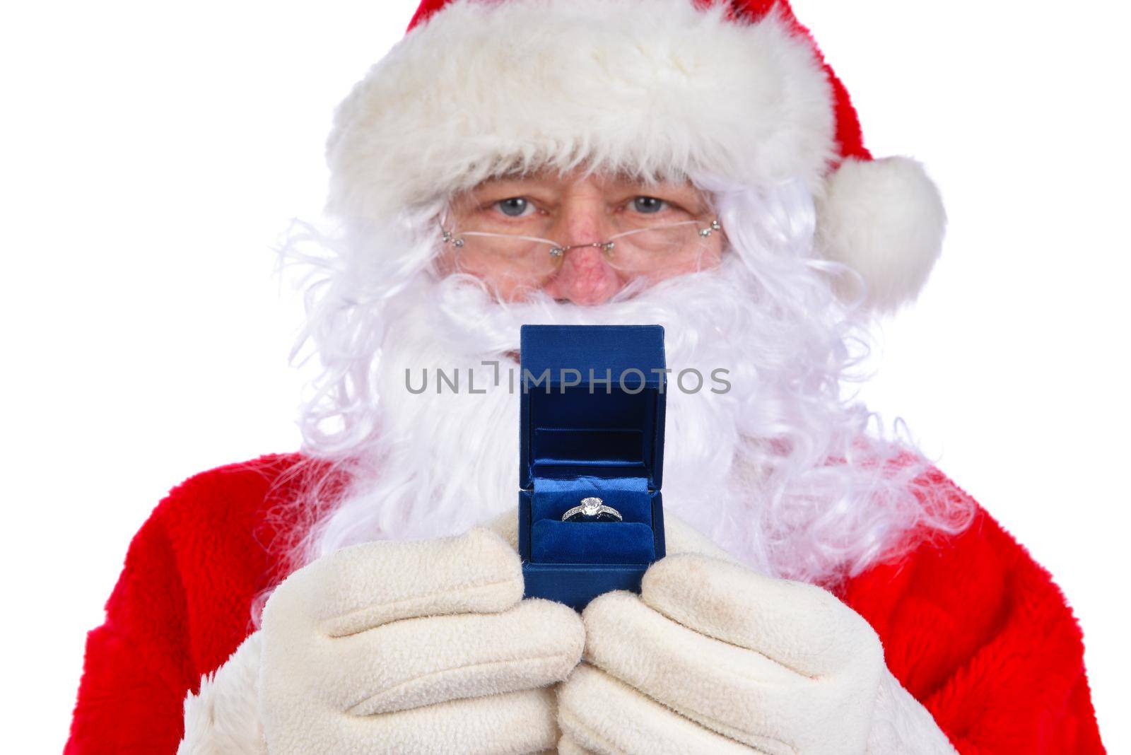 Santa Claus holding an diamond engagement ring in a blue box closeup in front of his face - focus is on ring by sCukrov