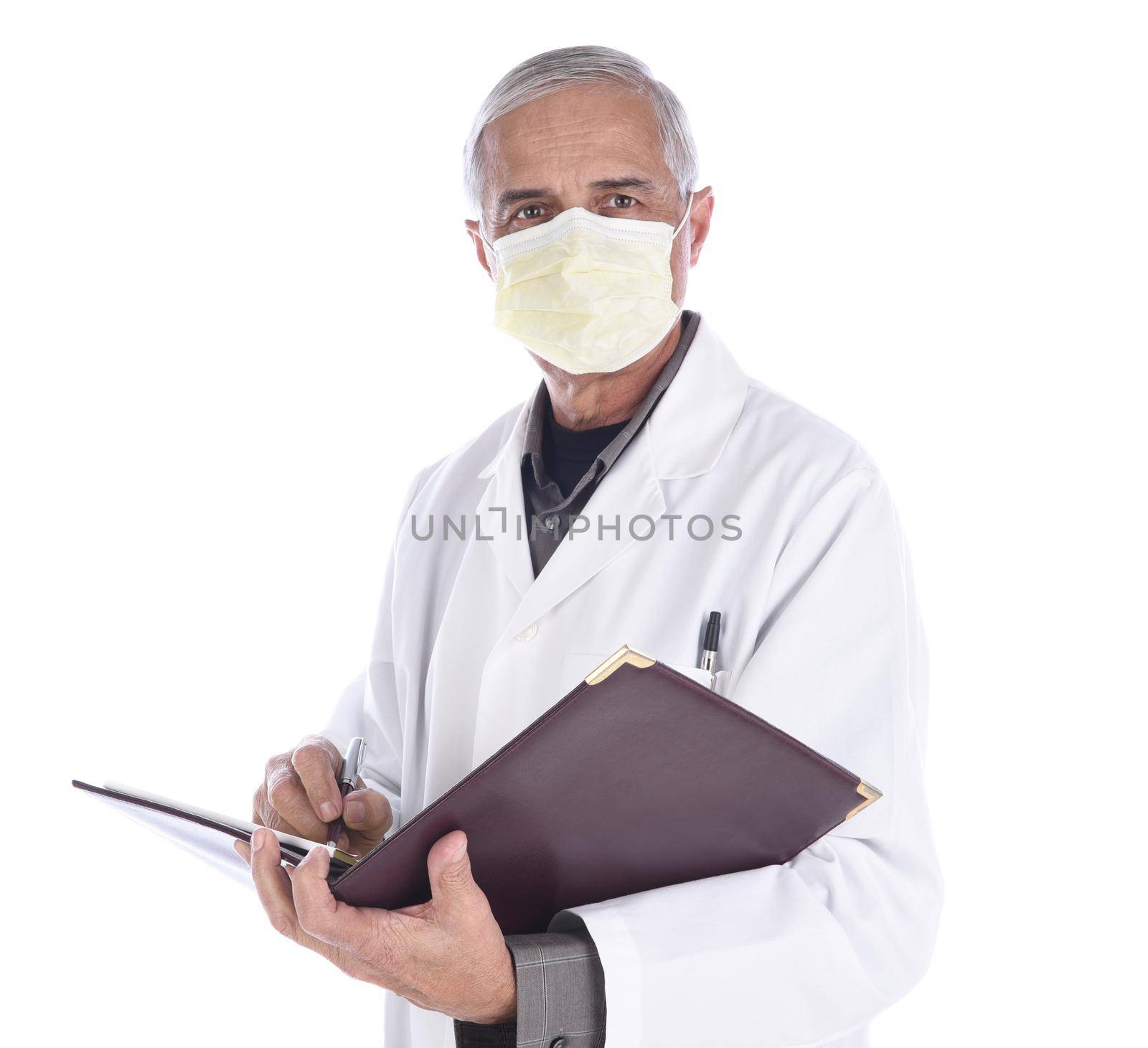 Portrait of a middle aged doctor wearing a surgical mask and lab coat writing in a notebook. Isolated on white.