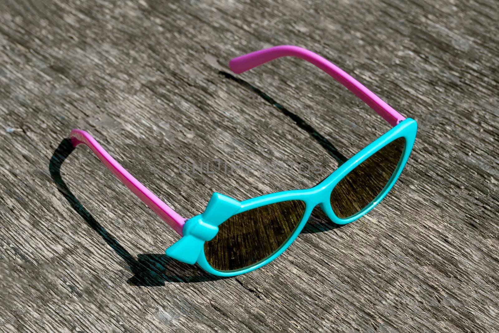 Blue sunglasses with pink arches on gray background. by Essffes