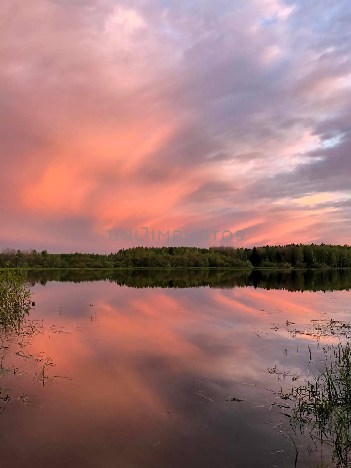 Dramatic sunset clouds over lake and trees - stock photo. High quality photo