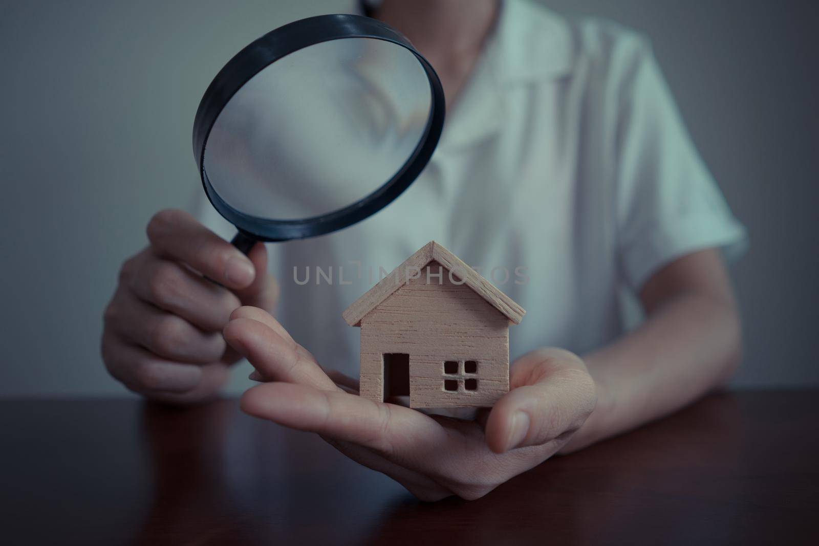 Concepts of home search for housing or home appraisal. Business Woman or bank officer using a magnifying glass to checking the model house. by pravinrus