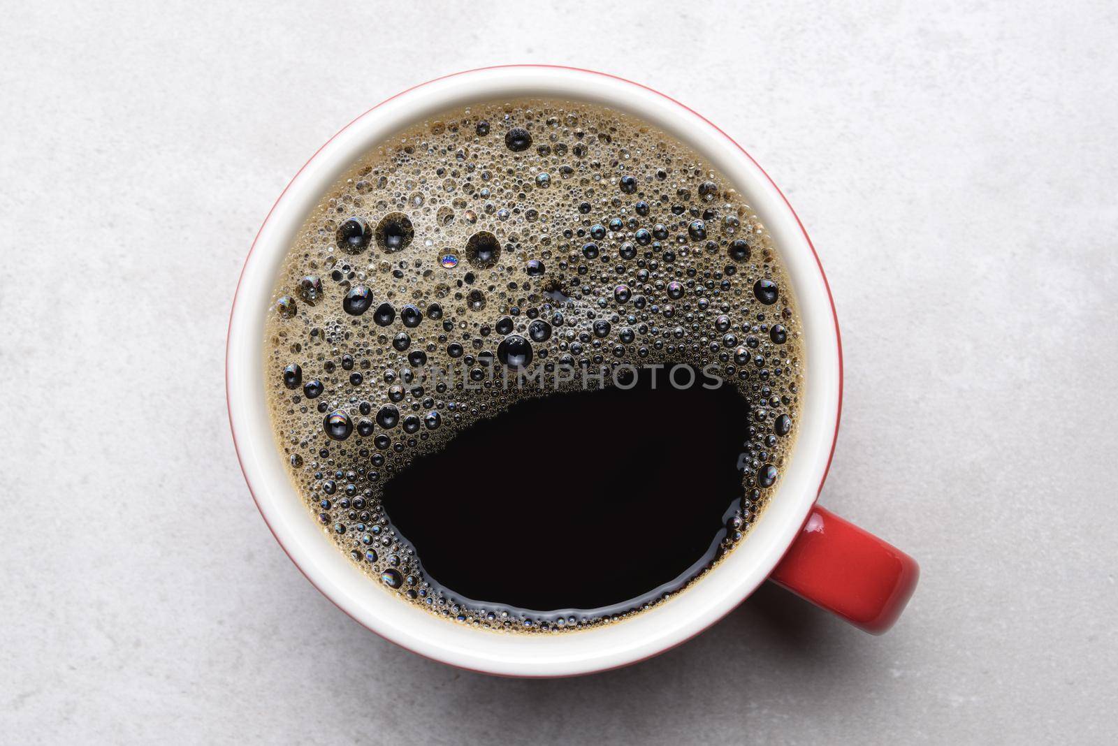Black coffee in red mug on light gray tile - top view