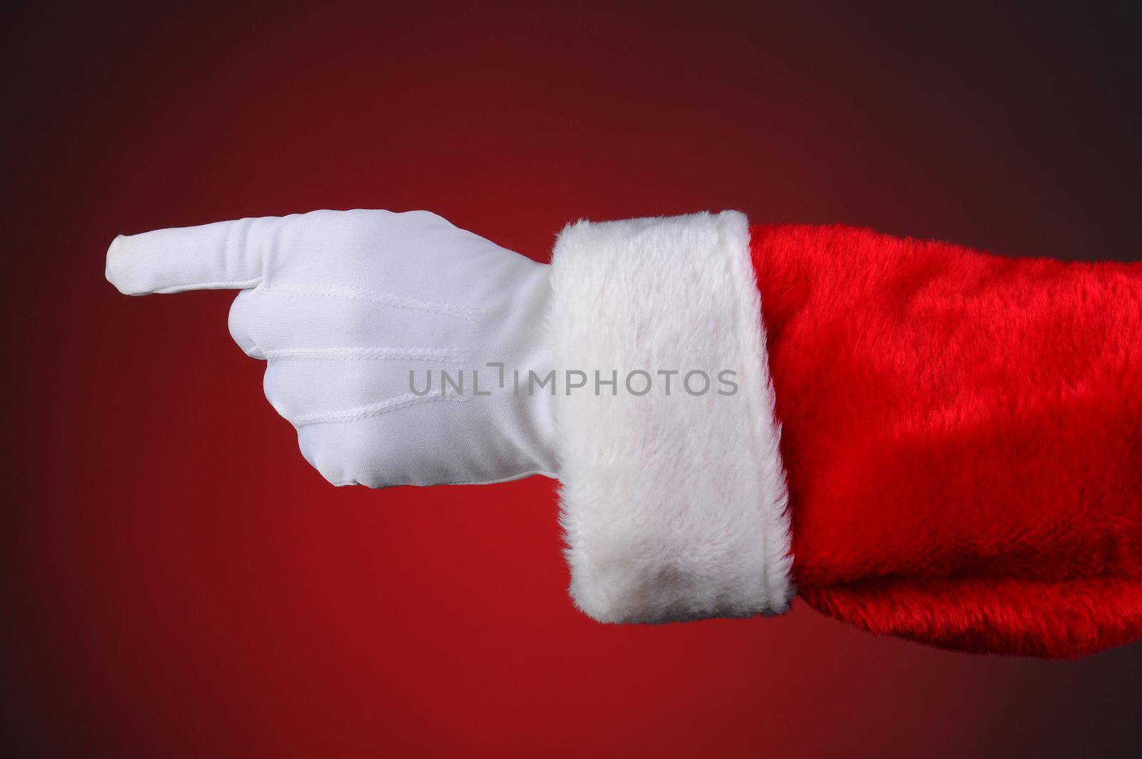 Santa Claus pointing, hand and arm only. Horizontal format over a light to dark red background.