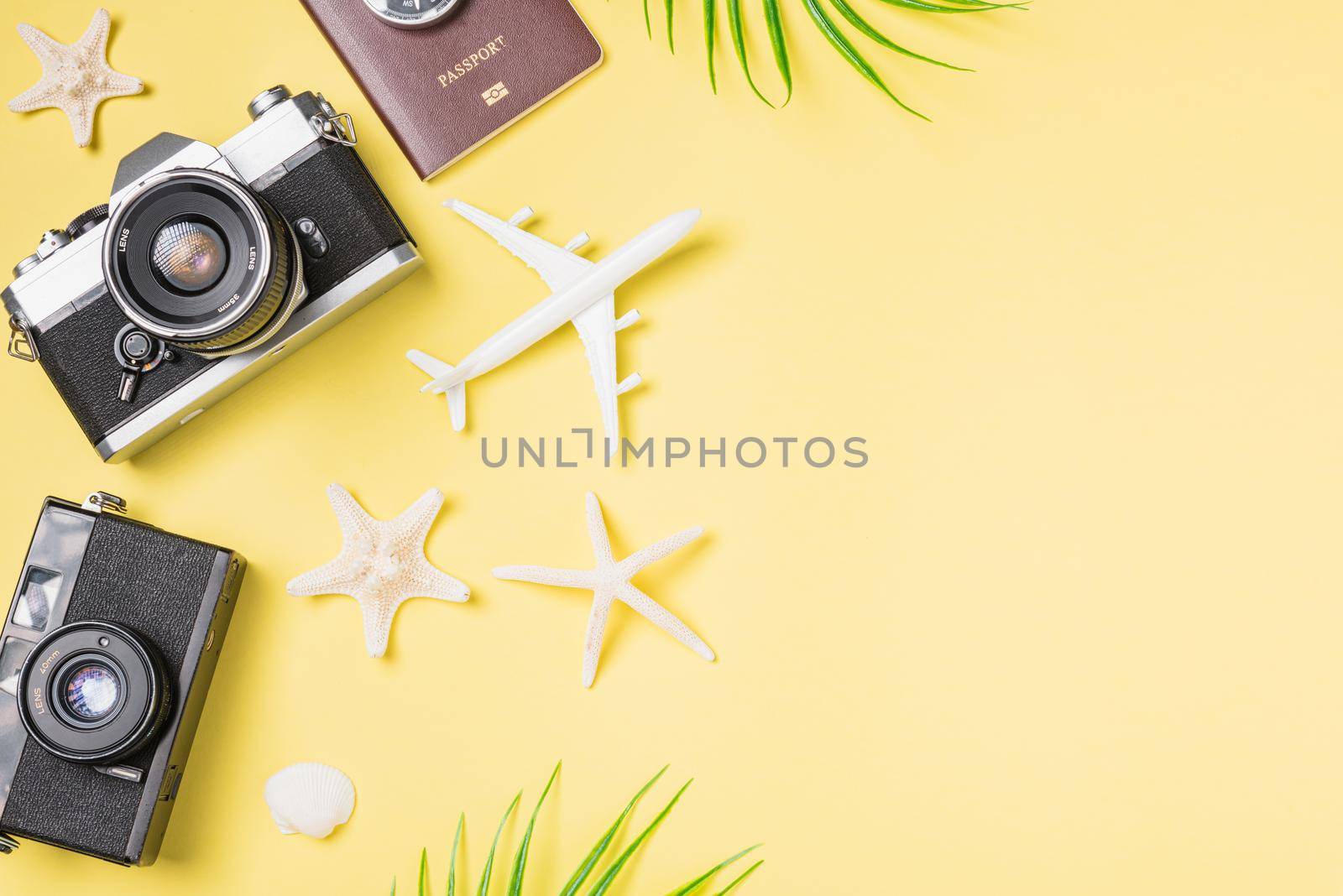 Flat lay top view mockup retro camera films, airplane, leaves, starfish traveler tropical beach accessories on a yellow background with copy space, Vacation summer travel and business trip concept