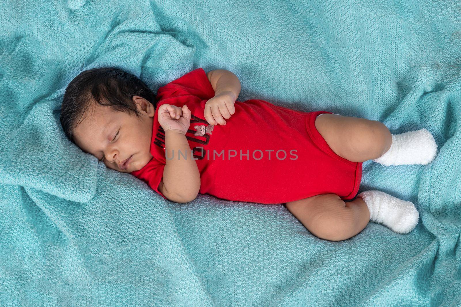 Infant asleep lying on his stomach, dressed in red clothes