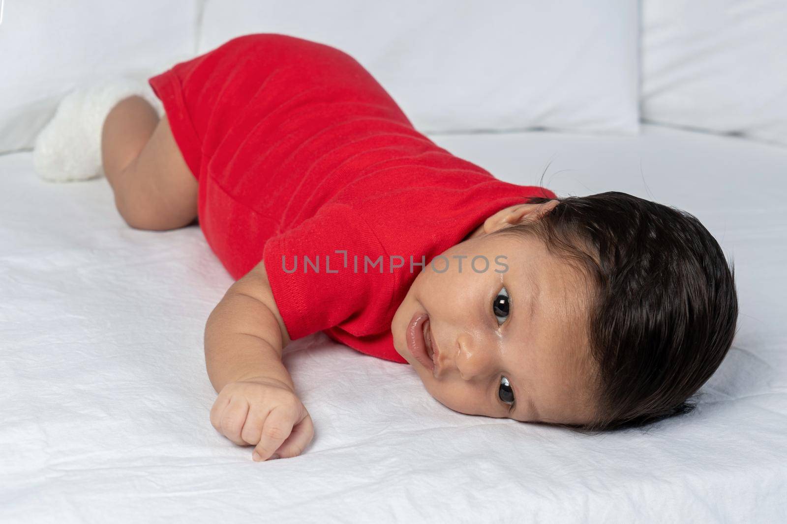 Infant lying on his stomach wearing red clothes