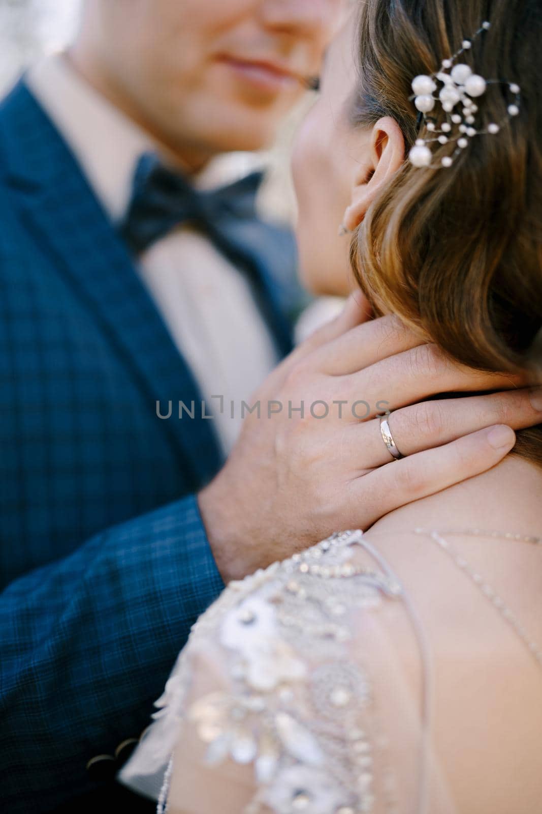 Groom touches bride neck with his hand. Back view. Close-up. High quality photo