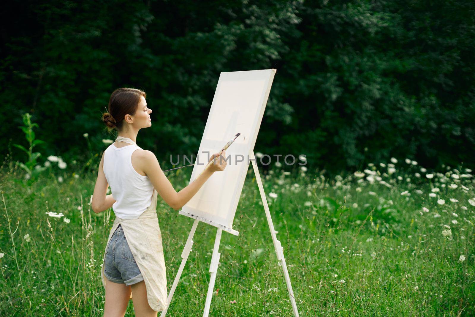 woman artist with palette of paints drawing easel nature hobby by Vichizh