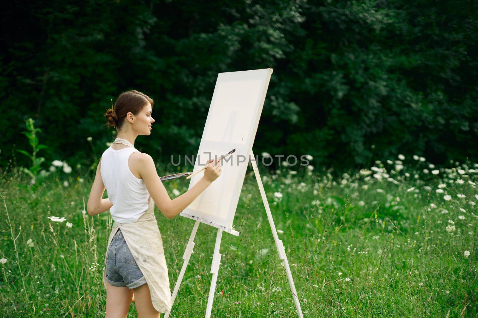 woman artist with palette of paints drawing easel nature hobby. High quality photo