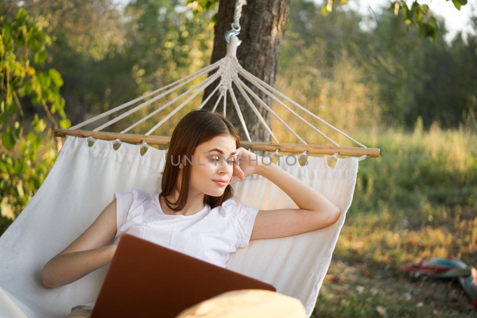 cheerful woman lies in a hammock with a laptop vacation internet travel by Vichizh