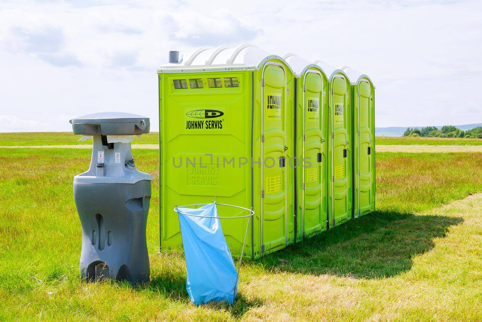 Skutech, Czech Republic, 26 June 2020: Portable toilet on the grass on a background of clouds. Mobile toilet.