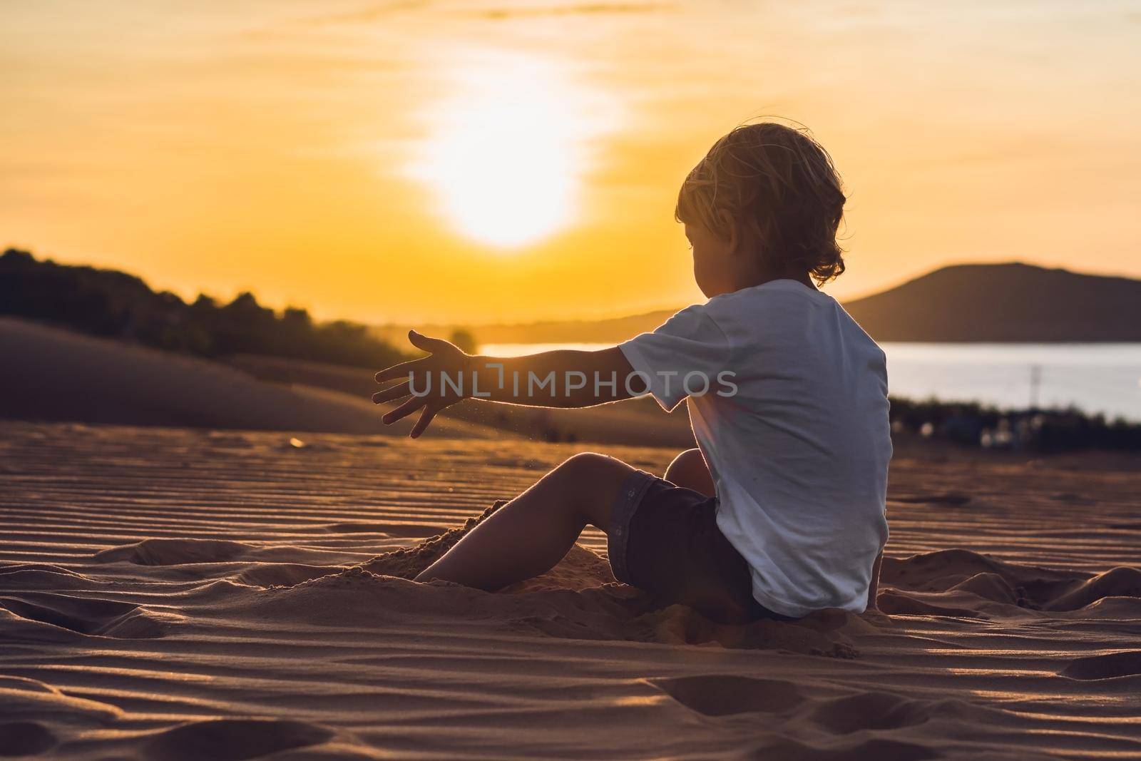 The boy in the red desert at dawn. Traveling with children concept.