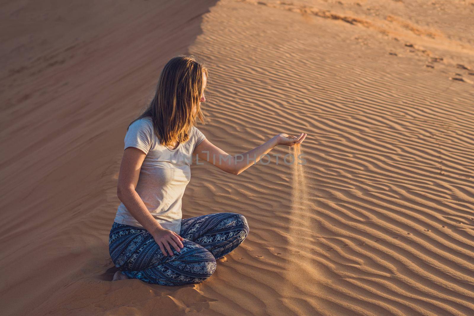 young woman in rad sandy desert at sunset by galitskaya
