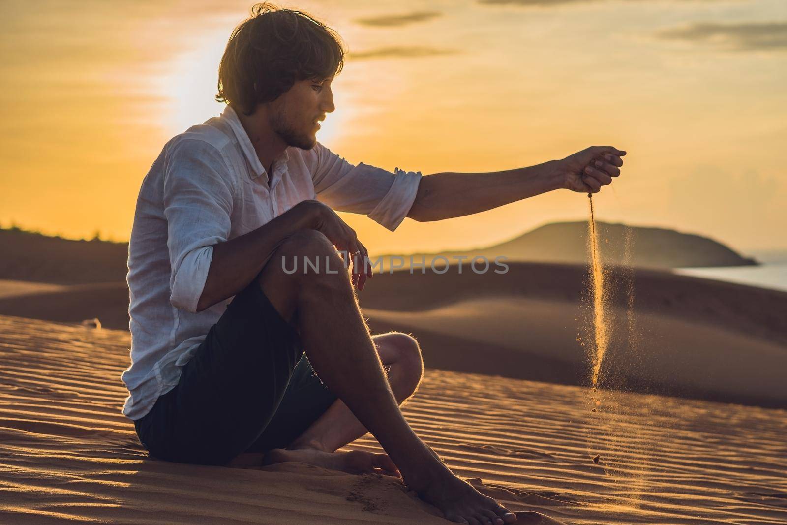 A man is pouring sand in the desert. Sand through the fingers of the concept by galitskaya