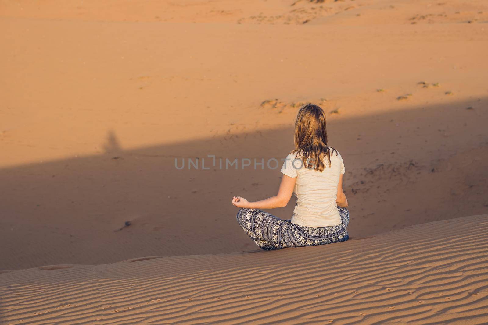 young woman meditating in rad sandy desert at sunset by galitskaya