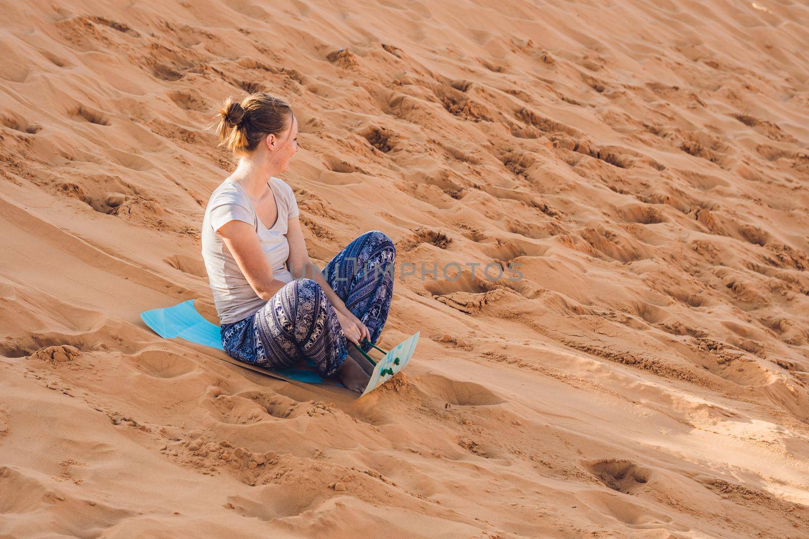 Young woman rolls on a toboggan in the sledge in the desert.