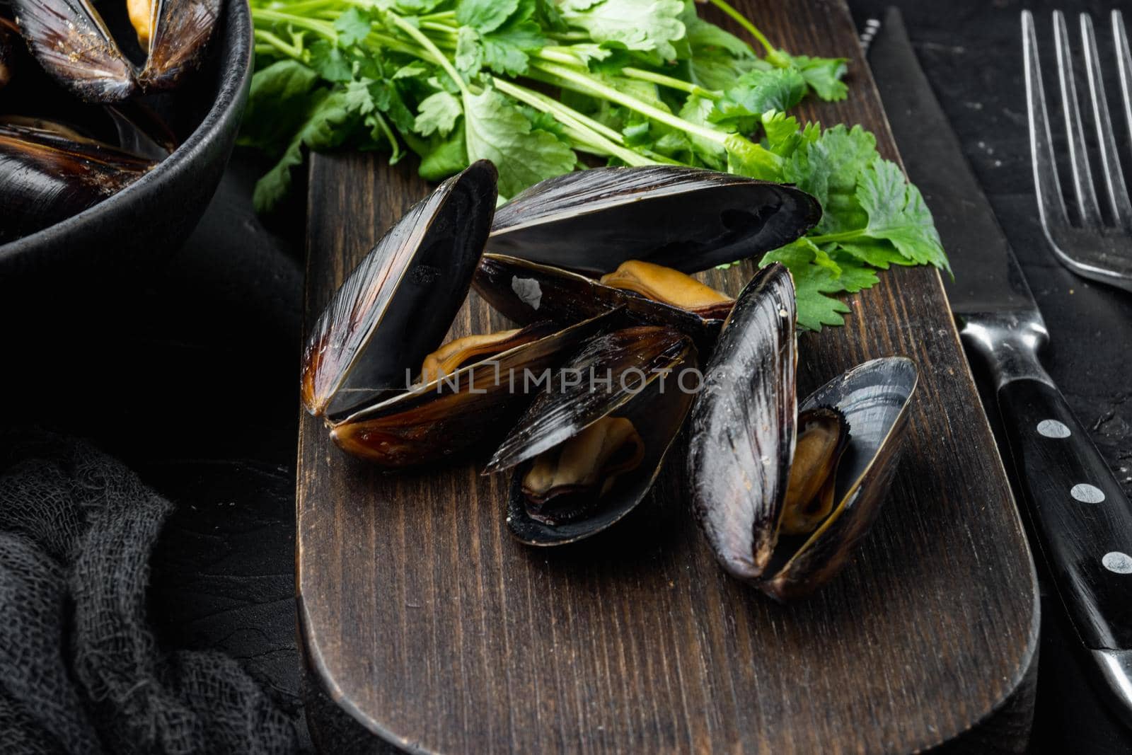 Boiled mussels with cheese sauce and garlic sauce, in bowl, on black background