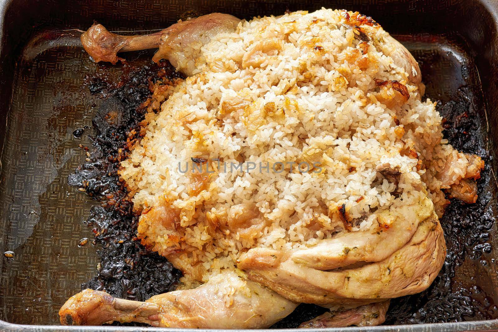 Burnt chicken stuffed with rice on a metal pan. Unsuccessful food preparation