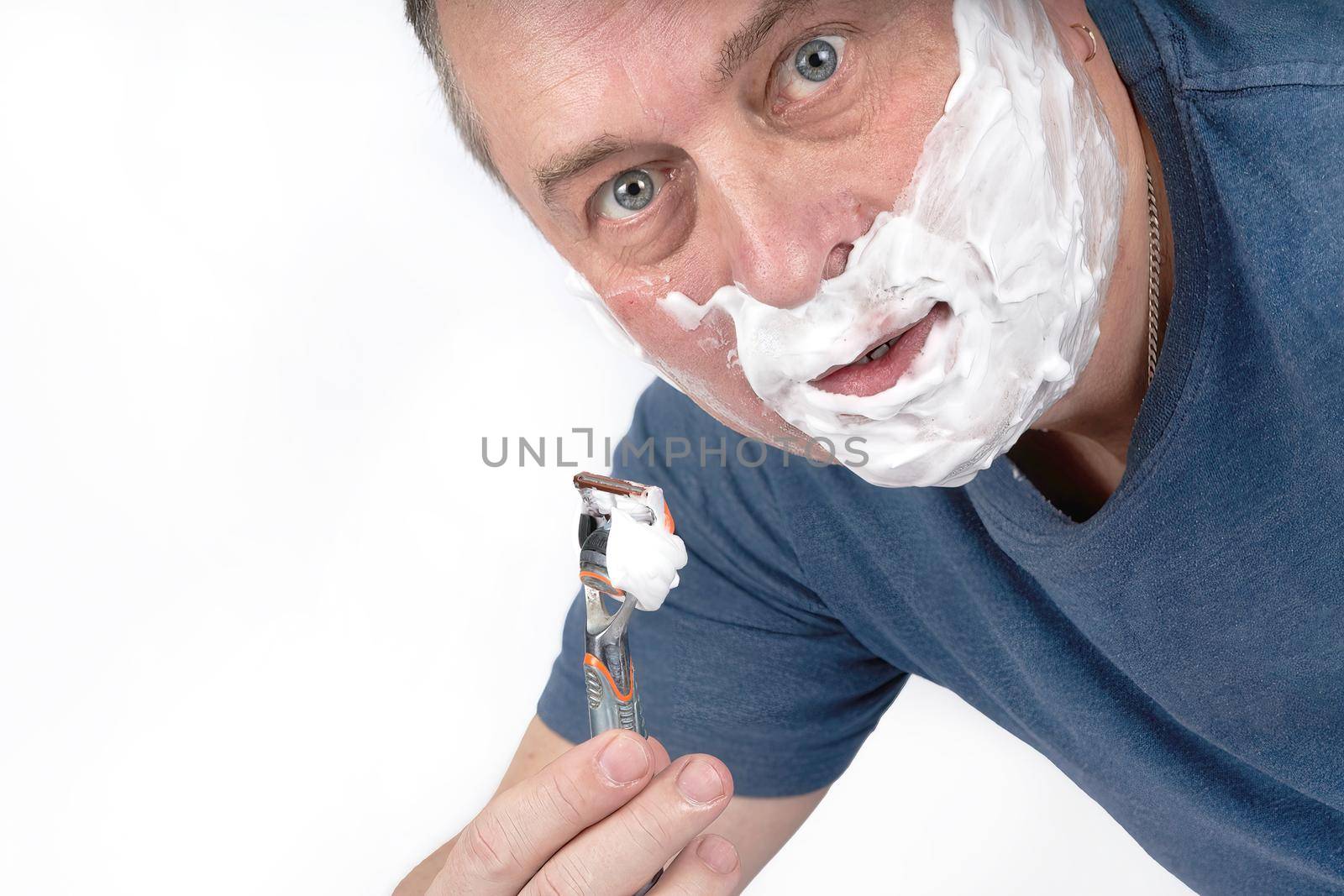 A man face in shaving foam shaves with a safety razor. Morning or evening exercise, personal hygiene