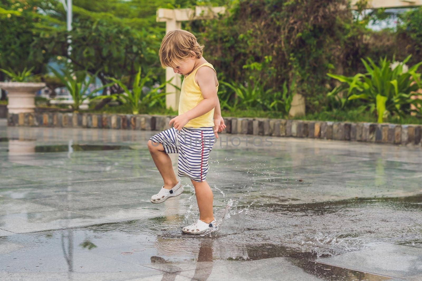 Little boy runs through a puddle. summer outdoor by galitskaya