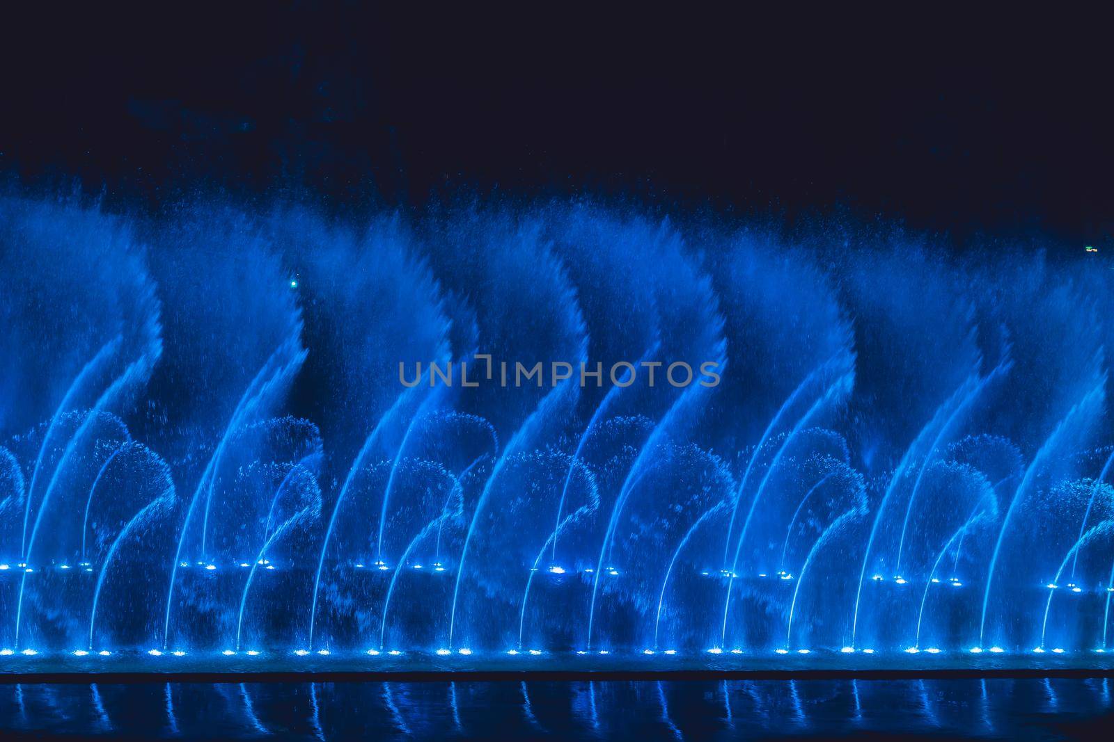 Multicolored dancing water jet fountain in the dark.