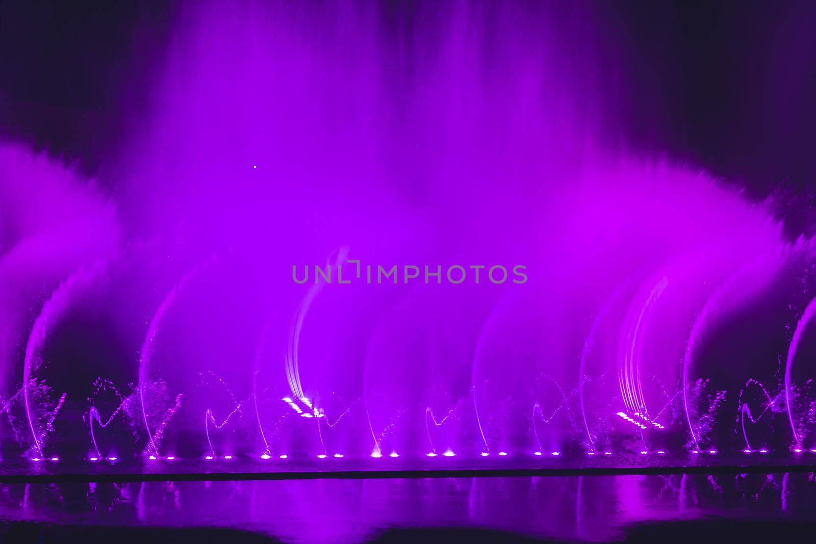 Multicolored dancing water jet fountain in the dark by galitskaya
