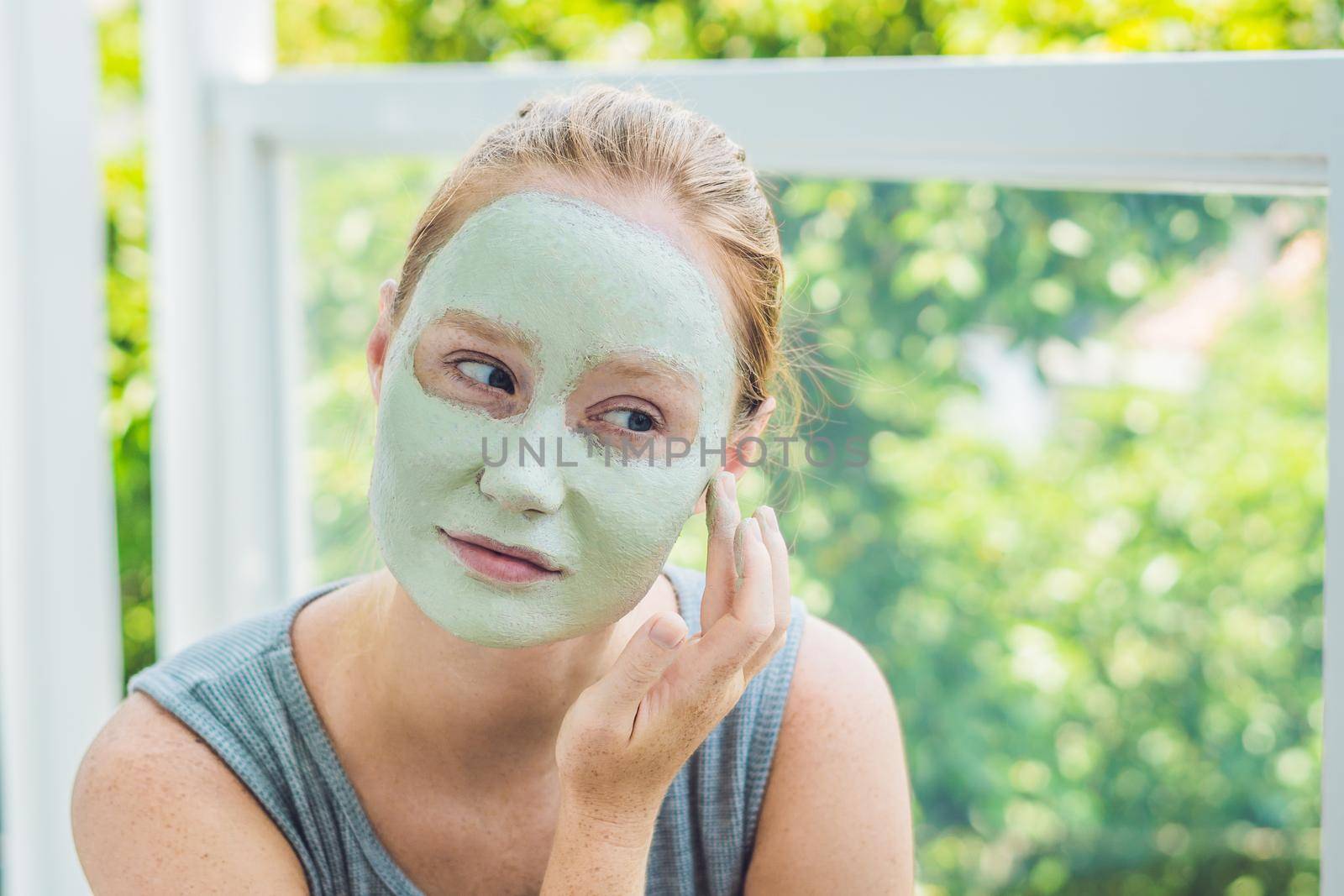Spa Woman applying Facial green clay Mask. Beauty Treatments. Close-up portrait of beautiful girl applying facial mask.