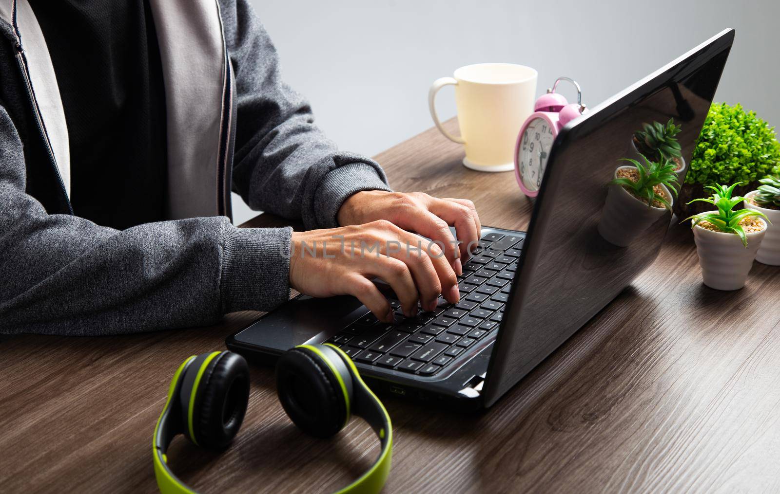 An Asian man uses a laptop at home while sitting at a wooden table. by tehcheesiong