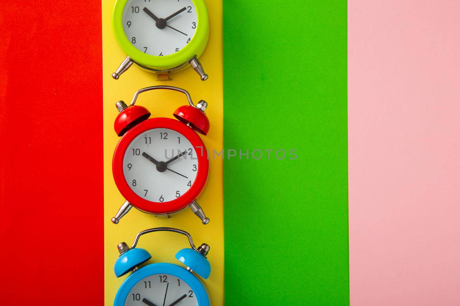 Colorful alarm clock on colorful background. (Flat lay)