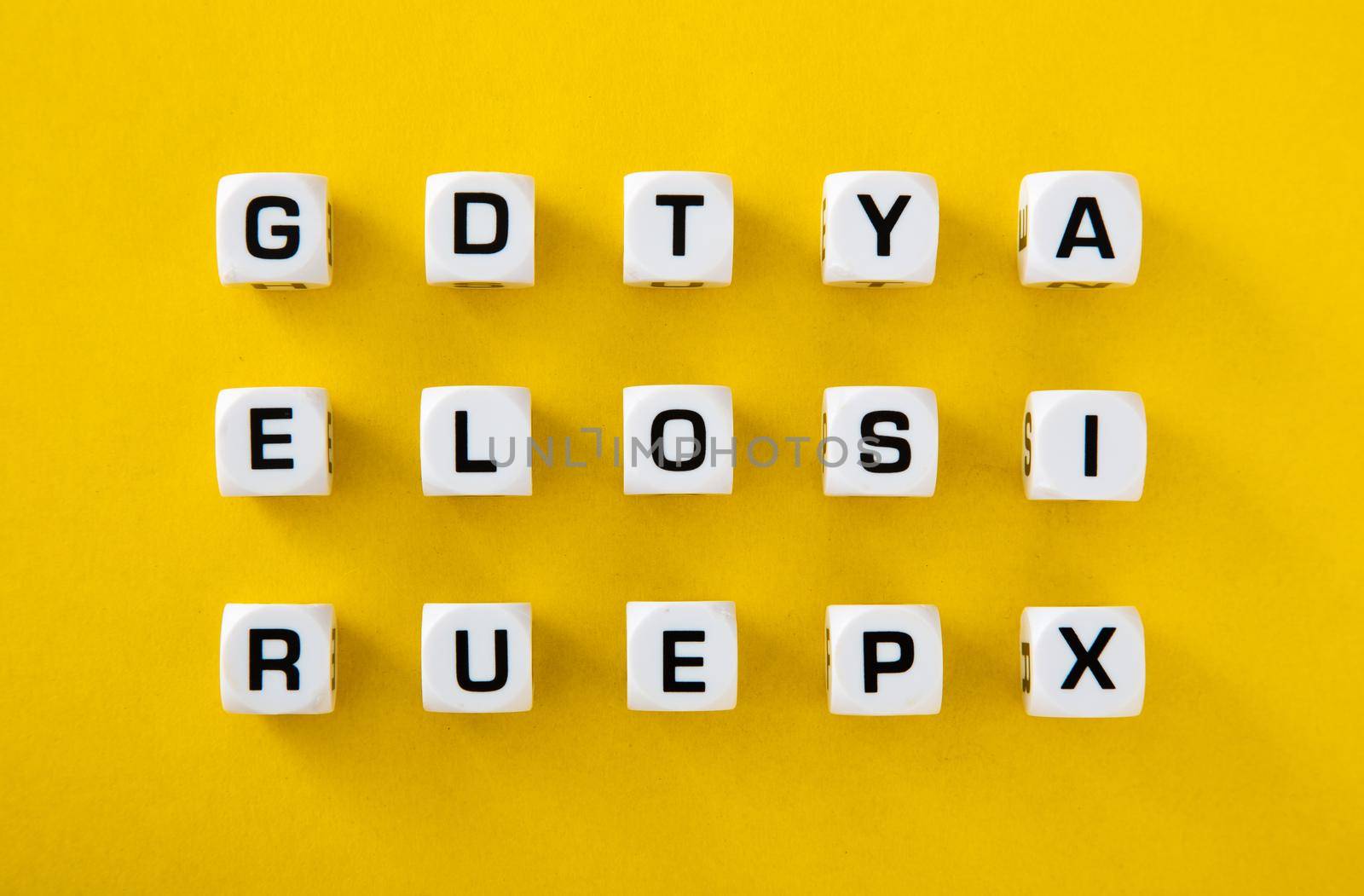 White cubes with letters scattered randomly on a yellow background