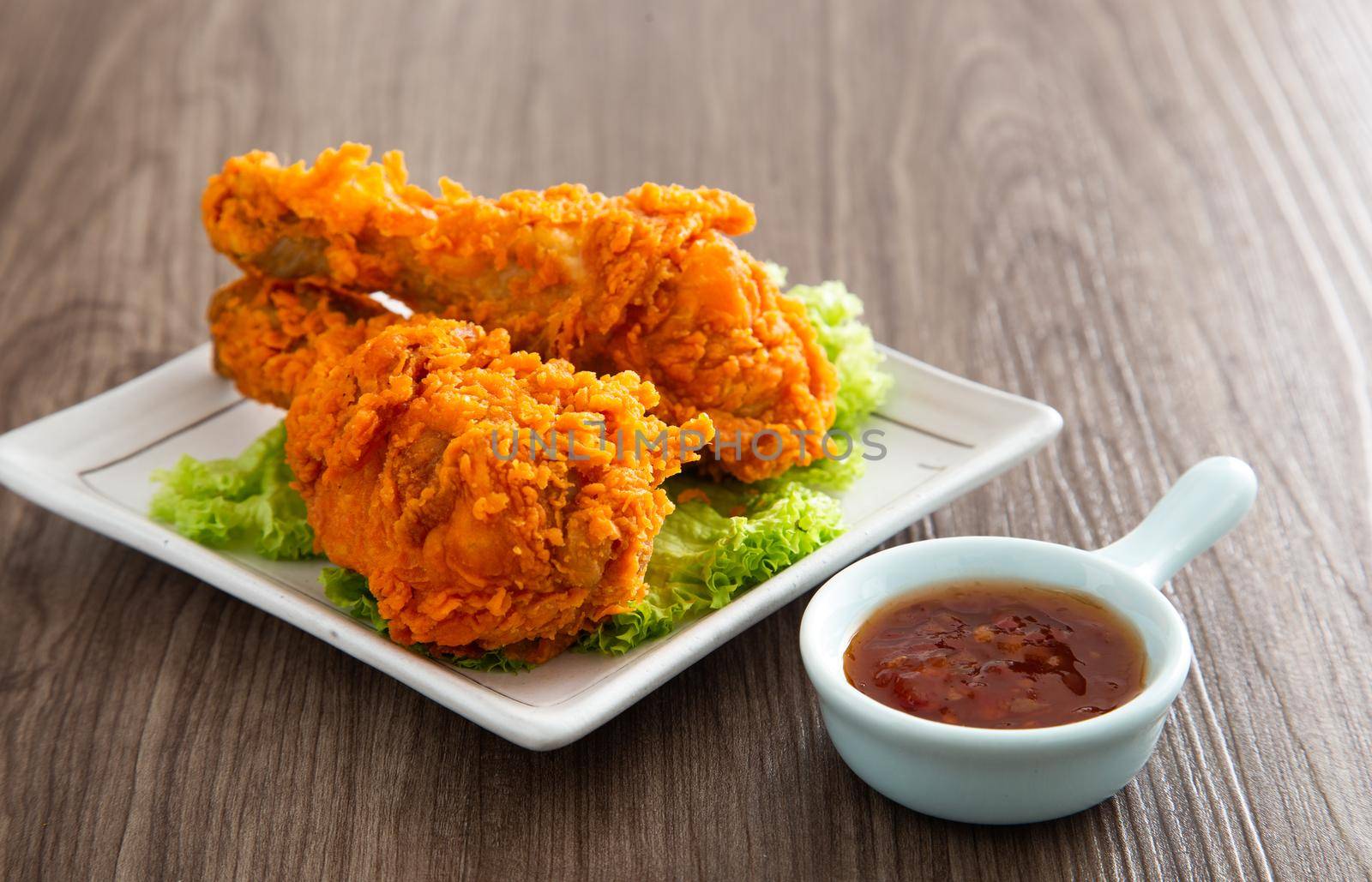 crispy and golden fried chickens with sauce on wooden table