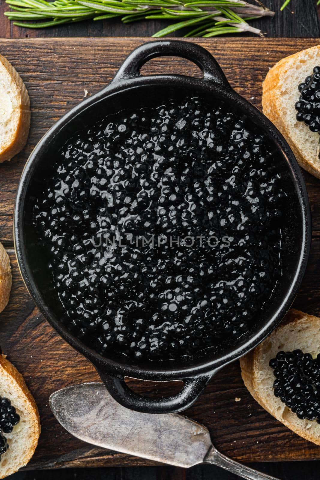 Canape with black sturgeon caviar, on old dark wooden table background, top view flat lay