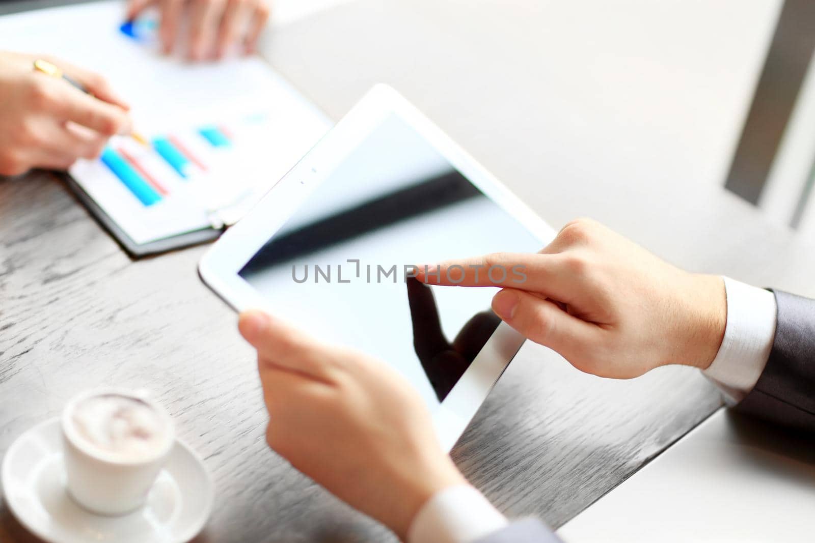Close-up of touchpad in businessman hands during meeting
