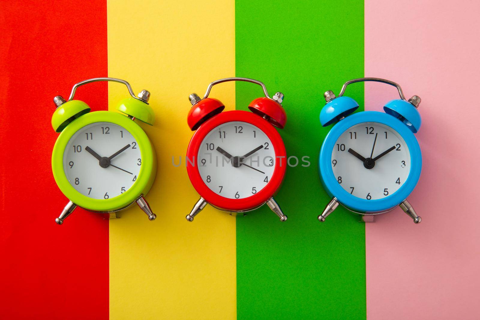 Colorful alarm clock on colorful background. (Flat lay)