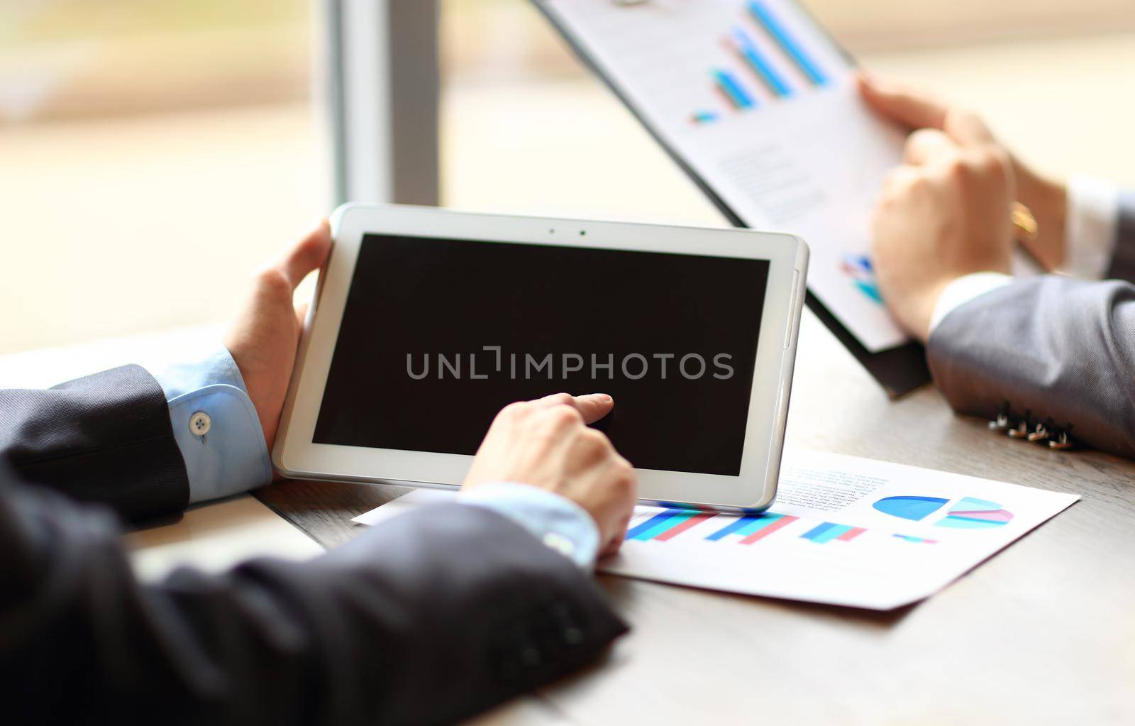 work of two young businessmen using touchpad at meeting