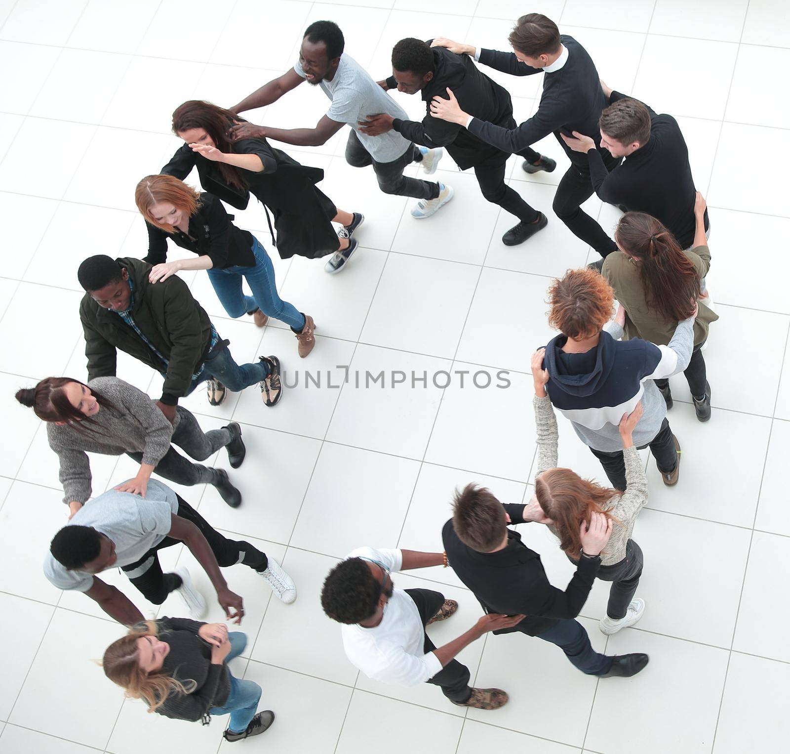 Large group of people seen from above, gathered in the shape of a circle, standing on a concrete backgroun