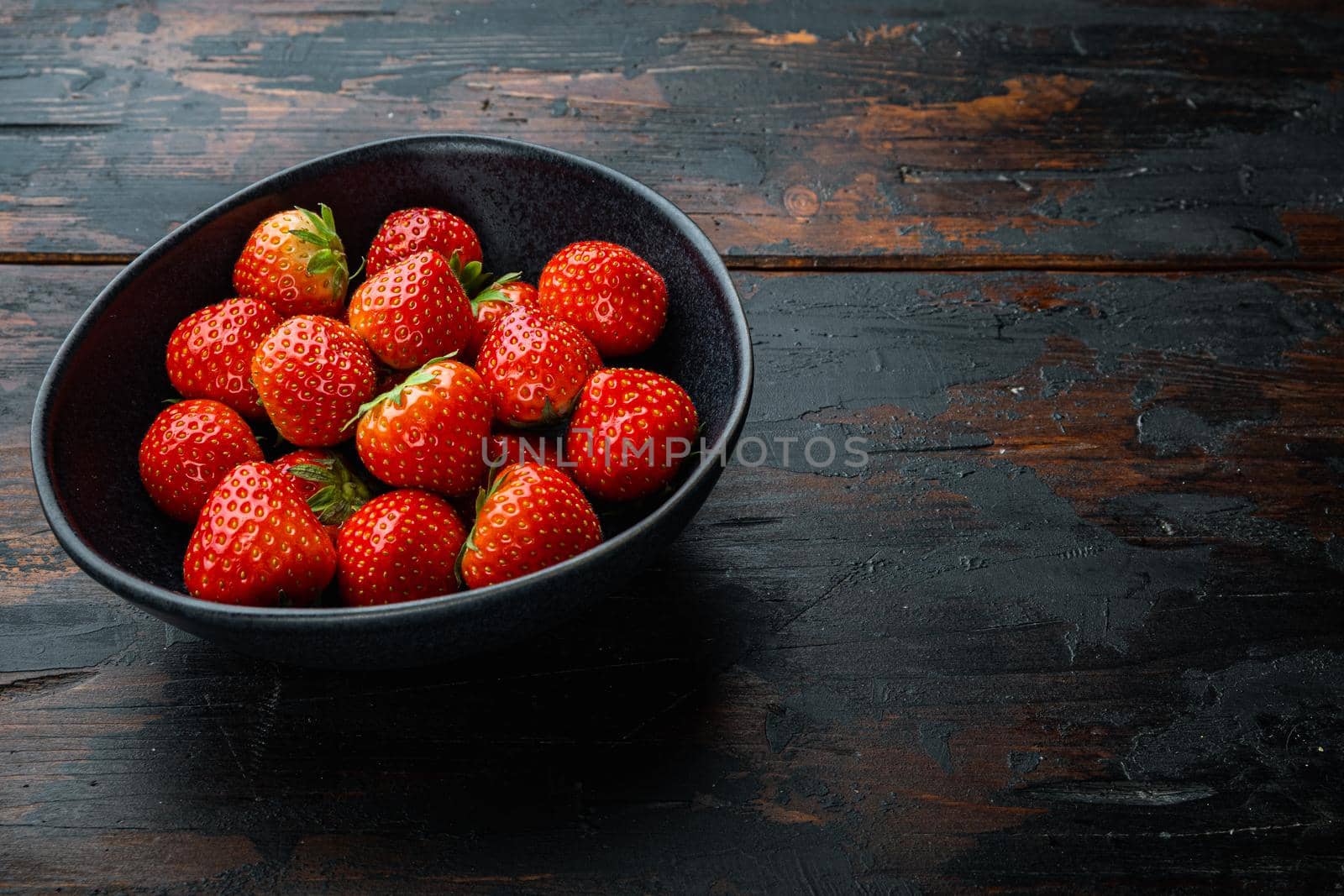 Ripe red strawberry with space for text on old wooden background.