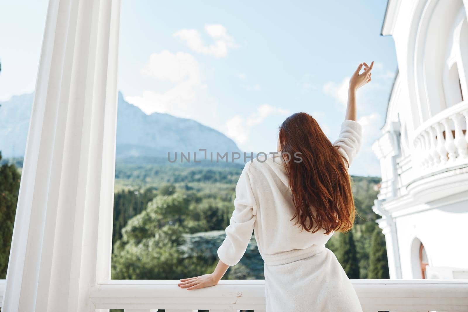 woman looks at a beautiful view from the balcony Perfect sunny morning by SHOTPRIME