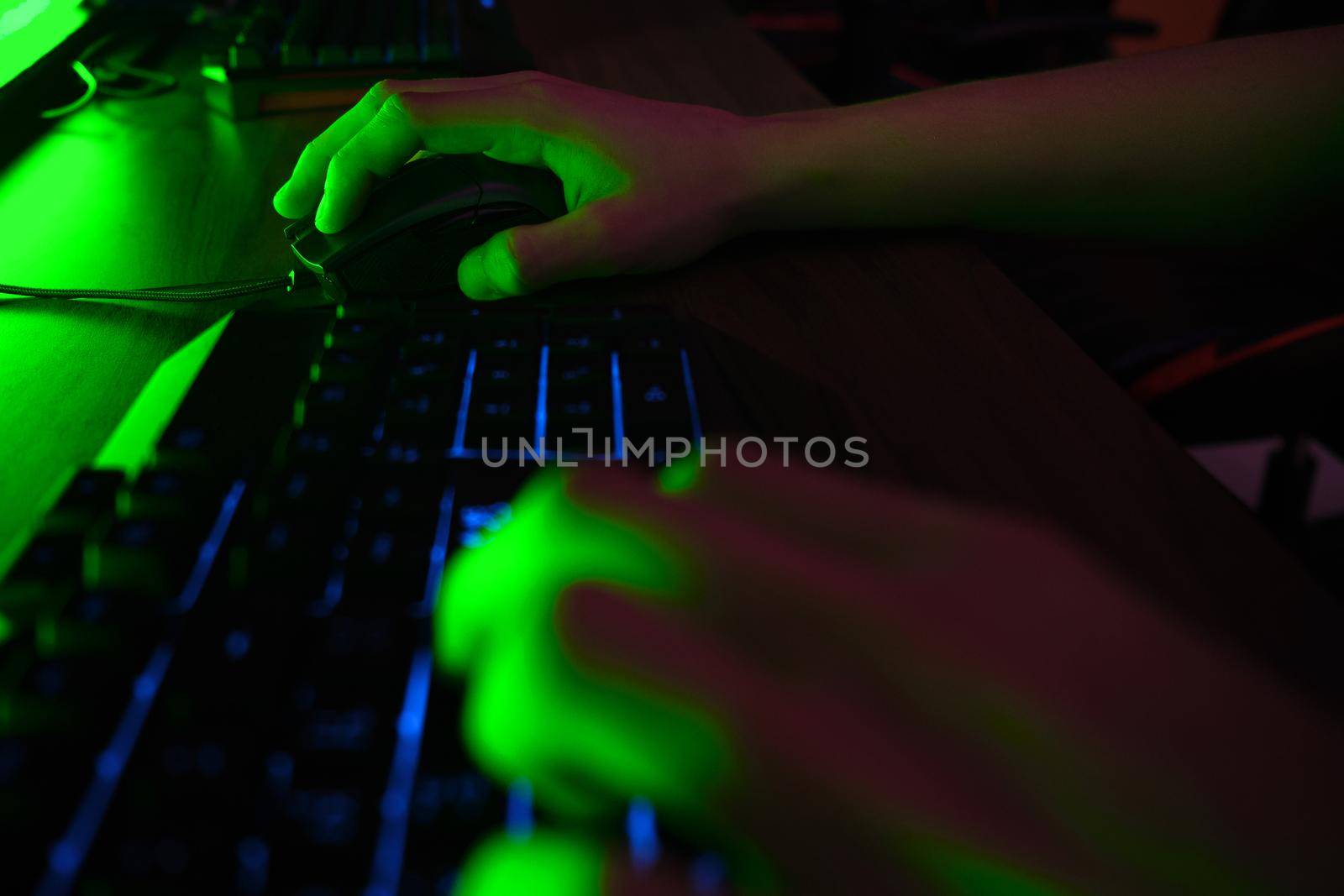 Close up view of professional players hands on gaming keyboard in gaming club or cyber arena. Green neon light