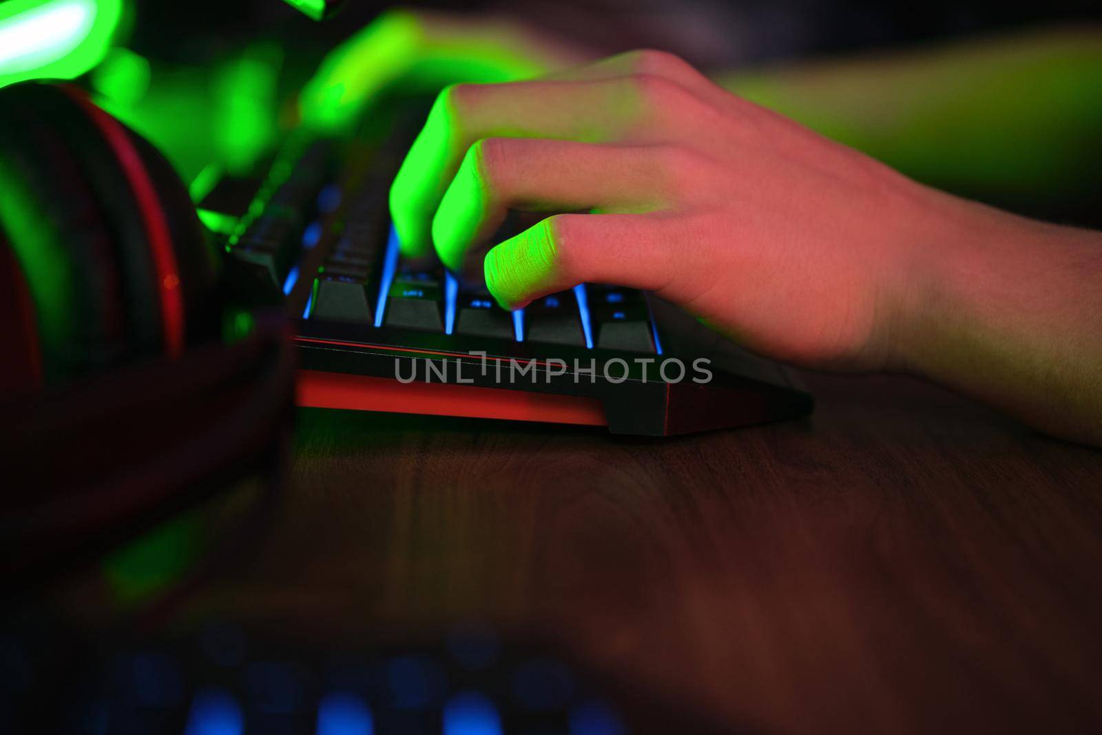 Close up view of professional players hands on gaming keyboard in gaming club or cyber arena. Green neon light