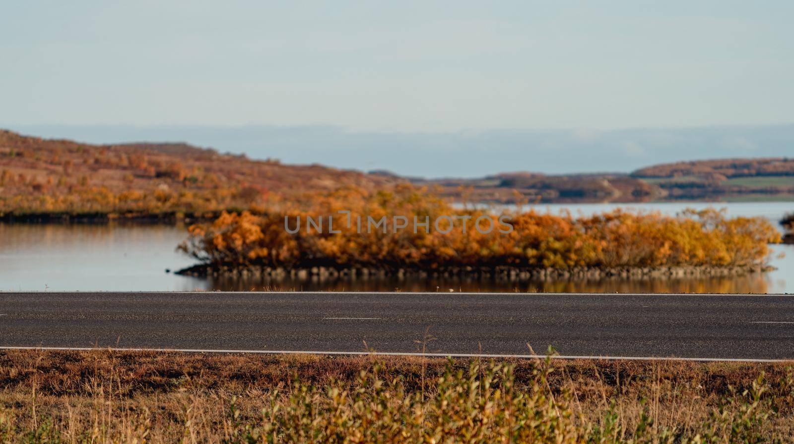 Isolated road on Autumn with blurred background and lake