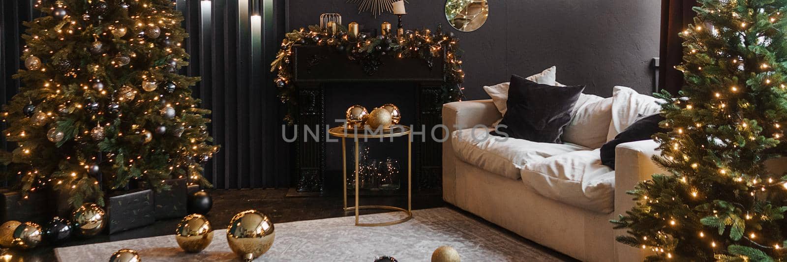 Christmas interior with a beautiful Christmas tree, sofa, light bulbs and dark background. Home New Year's interior.
