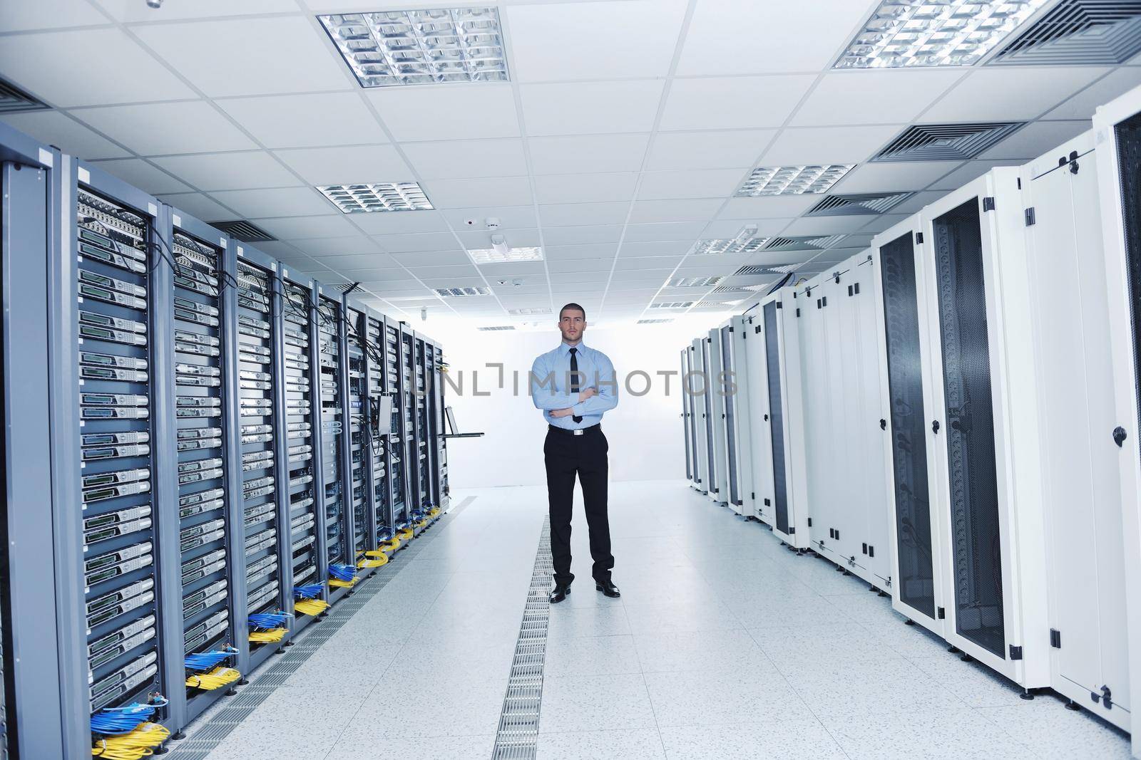 young it engineer in datacenter server room by dotshock