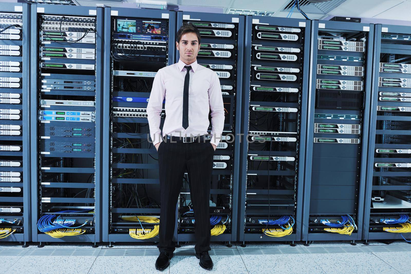 young it engineer in datacenter server room by dotshock