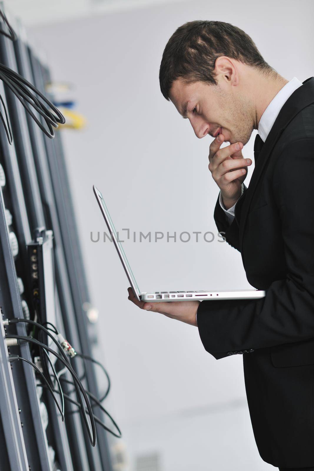 businessman with laptop in network server room by dotshock