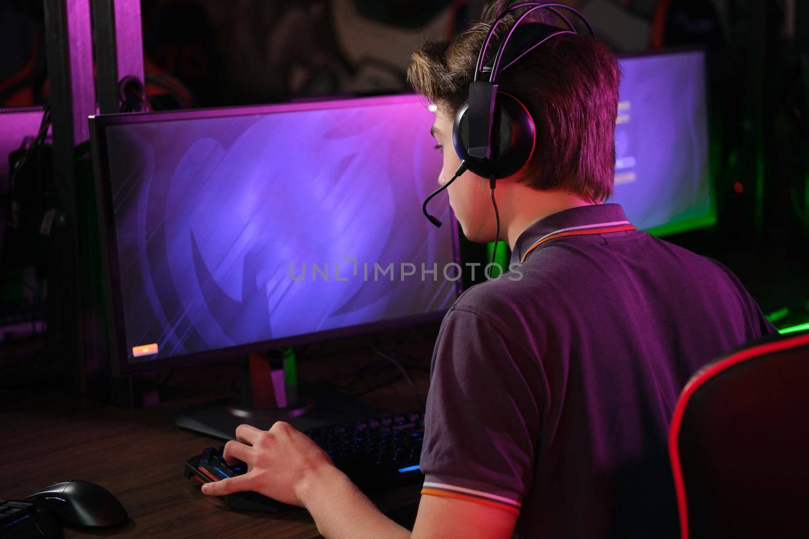 Professional photo of young male caucasian cyber sportsman in gaming club training for important match. Back view
