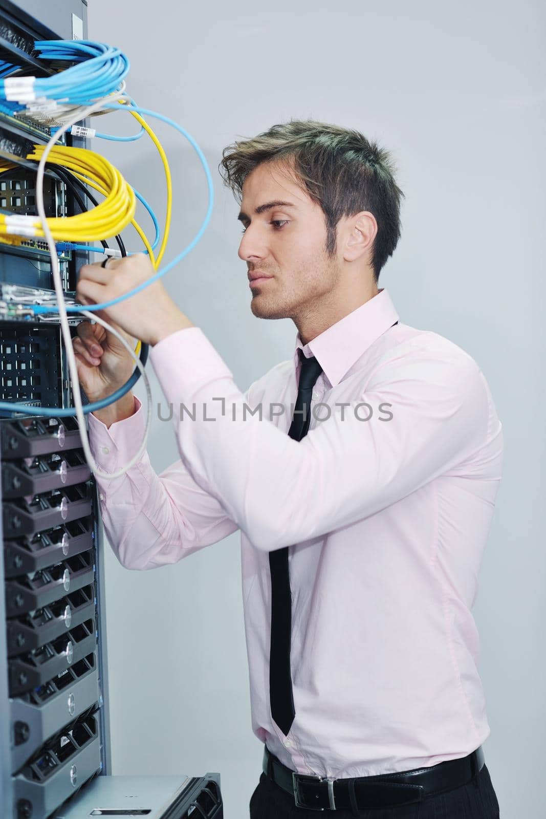 young it engineer in datacenter server room by dotshock