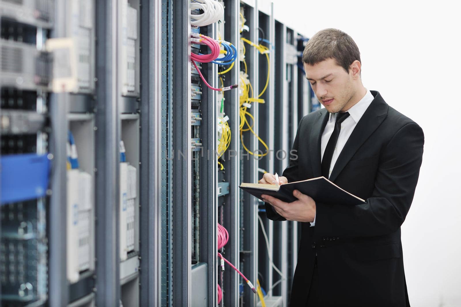 young it engeneer business man with notebook  in network server room
