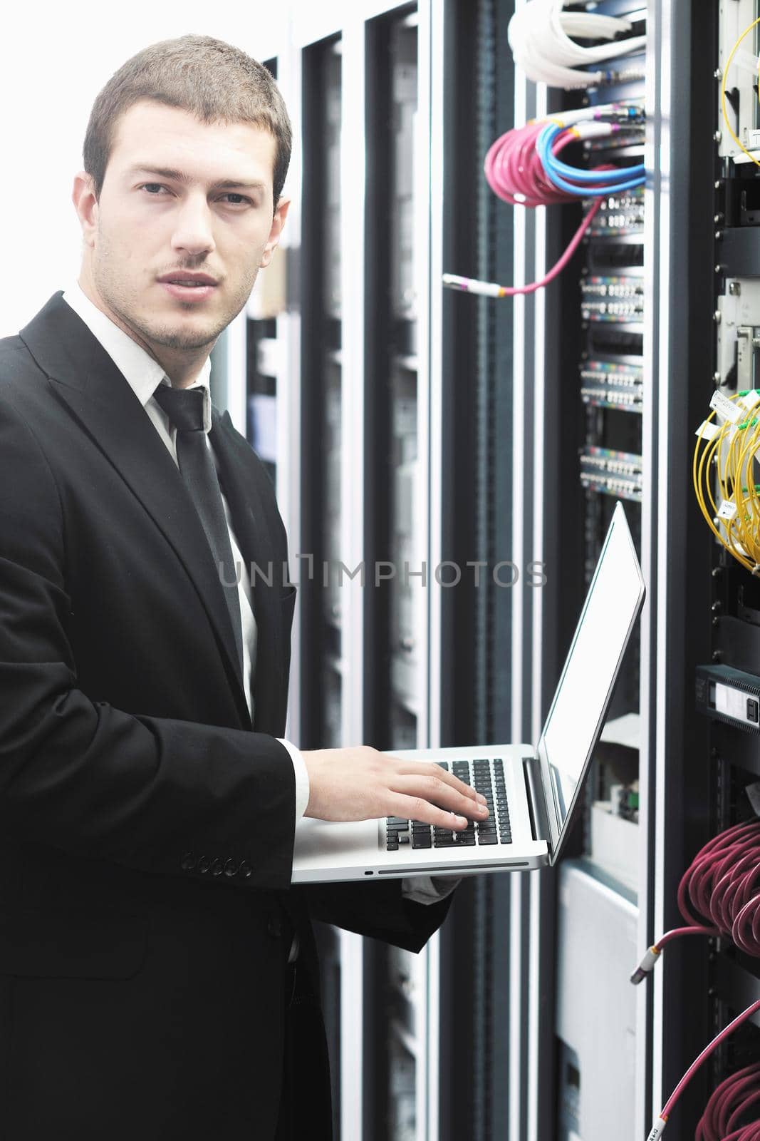 businessman with laptop in network server room by dotshock